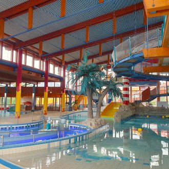 © Wonnemar Sonthofen | interSPA Gruppe A modern leisure pool with a large water basin and various slides. Palm trees create a tropical atmosphere. | © Wonnemar Sonthofen | interSPA Gruppe