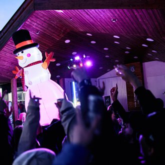 © Kleinwalsertal Tourismus | Oliver Farys A festive event with a large snowman puppet and many celebrating people. Colorful lights illuminate the scene. | © Kleinwalsertal Tourismus | Oliver Farys