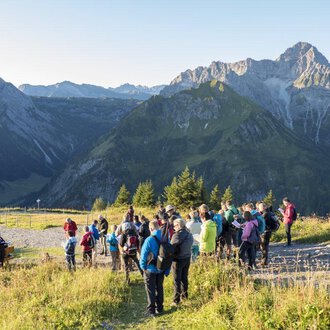 © OK-Bergbahnen A group of hikers enjoys the view of the mountains. The sky is clear, and nature provides an impressive backdrop. | © OK-Bergbahnen