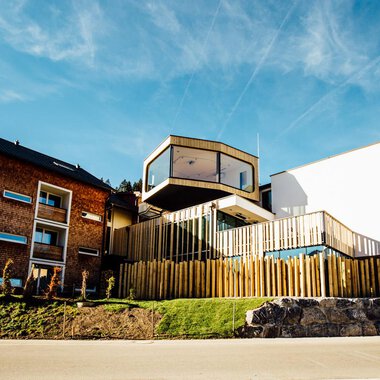 A modern building with wooden cladding and large windows. The architecture combines traditional and contemporary elements. | © Genuss- und Aktivhotel Sonnenburg | Andi Mayr