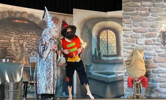 A theater performance featuring two characters in imaginative costumes. In the background, hand-painted scenery of an old room is visible. | © KiWi Kindertheater GbR