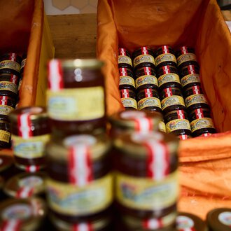 © Kleinwalsertal Tourismus | Oliver Farys A variety of small jars of jam are placed in orange baskets. The jars are arranged in rows and have colored labels. | © Kleinwalsertal Tourismus | Oliver Farys