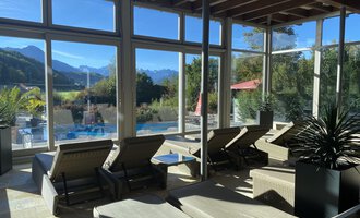 © Wonnemar Sonthofen | interSPA Gruppe A bright relaxation room with loungers and large windows. In the background, mountains and a pool are visible. | © Wonnemar Sonthofen | interSPA Gruppe