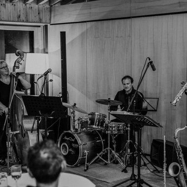 © Naturhotel Chesa Valisa Three musicians are happily gathered together, playing various instruments. In the background, the nature hotel can be seen. | © Naturhotel Chesa Valisa