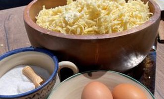 A wooden bowl with freshly grated cheese is on a table. Next to it are a bowl of eggs and a container of salt. | © Gerd am Herd | Gerd Hammerer