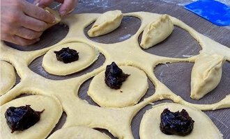 Someone is shaping dough on a wooden surface. There is a dark brown filling on the dough. | © Gerd am Herd | Gerd Hammerer