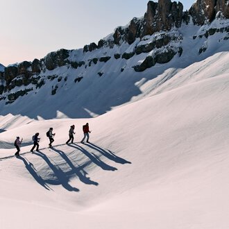 © Kleinwalsertal Tourismus eGen | Oliver Farys A group of hikers is walking through a snowy landscape. Majestic mountains can be seen in the background. | © Kleinwalsertal Tourismus eGen | Oliver Farys