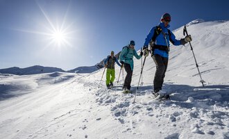 © Kleinwalsertal Tourismus eGen | Dominik Berchtold A group of people is hiking through a snowy landscape. The sun is shining clearly in the sky. | © Kleinwalsertal Tourismus eGen | Dominik Berchtold