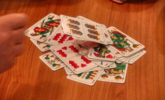 © Chesa Valisa A stack of cards lies on a wooden table. A hand is visible, encircling the cards. | © Chesa Valisa