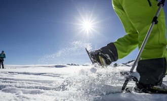 © Kleinwalsertal Tourismus | Dominik Berchtold A sunny day in the snow with a person working in the snow with a ski pole. In the background, another person can be seen. | © Kleinwalsertal Tourismus | Dominik Berchtold