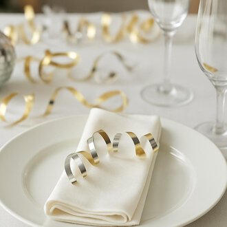 Ein festlich gedeckter Tisch mit einer roten Kerze und einem Weihnachtsstern. Die Dekoration ist von Tannenzweigen und Beeren umgeben. | © KI generiert Kleinwalsertal Tourismus