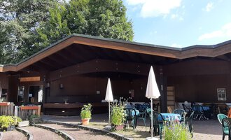 A cozy café with a wooden façade and terrace furniture. Surrounded by plants and trees, it invites you to relax. | © Kulturcafe Kleinwalsertal | Veronika Senn