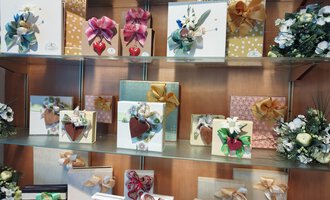 © Kleinwalsertal Tourismus | N. Lughammer A display case with beautifully wrapped gifts in various colors and adorned with artistic bows. The gifts come in different sizes, and some have heart or floral motifs. | © Kleinwalsertal Tourismus | N. Lughammer