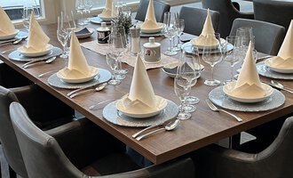 An elegantly set table with folded napkins and glasses. The table is prepared for a festive event.