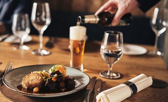 A set table with a plate of delicious food and a glass of beer. An elegant atmosphere with wine and water glasses. | © Travel Charme Ifen Hotel
