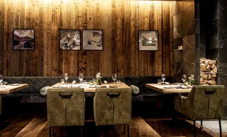 A modern restaurant with wooden walls and stylish furniture. The tables are elegantly set, and pictures hang on the wall. | © Travel Charme Ifen Hotel