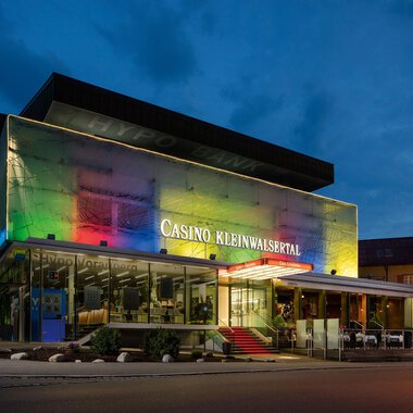 A modern casino with colorful lights at dusk. It is located in the Kleinwalsertal and has stylish architecture. | © Casinos Austria | Arnd Ötting
