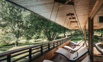 © Naturhotel Chesa Valisa | Heldentheater Eine entspannende Veranda mit modernen Liegen und Blick auf einen grünen Garten. Die Holzdecke und die natürliche Umgebung schaffen eine ruhige Atmosphäre. | © Naturhotel Chesa Valisa | Heldentheater