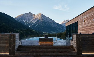 © Travel Charme Ifen Hotel Ein Infinity-Pool mit Blick auf majestätische Berge. Die Holzveranda schafft eine gemütliche Atmosphäre in der Natur. | © Travel Charme Ifen Hotel