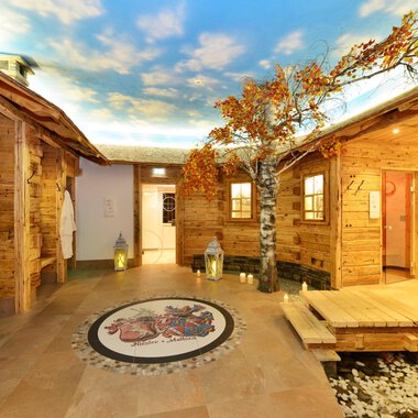 Ein gemütlicher Wellnessbereich mit Holzverkleidungen und einer schönen Baumdekoration. Die Decke zeigt einen klaren Himmel, der eine entspannende Atmosphäre schafft. | © Hotel Alpenstüble Appartements | Manuel Riezler