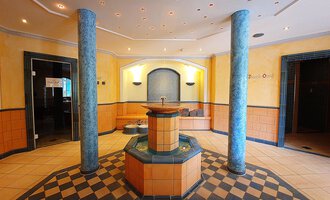 © Hotel Birkenhöhe An elegant wellness area with a central fountain. The walls are designed in warm colors, and the floor has a striking checkerboard pattern. | © Hotel Birkenhöhe