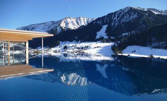 © Hotel Erlebach | Kristin Winter Ein Infinity-Pool mit Blick auf schneebedeckte Berge. Der klare Himmel und die ruhige Wasseroberfläche reflektieren die winterliche Landschaft. | © Hotel Erlebach | Kristin Winter