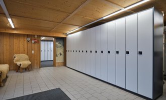 © Sport Kessler GmbH A modern changing room with white lockers against one wall. The room has a wooden ceiling and tiled floor. | © Sport Kessler GmbH