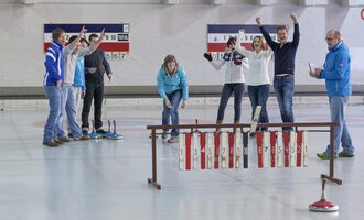 © Sportstätten Oberstdorf | Marc Vogel A group of people is celebrating on a curling rink. They display joy and enthusiasm while playing. | © Sportstätten Oberstdorf | Marc Vogel