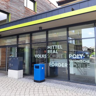 A modern school building with large windows and an inviting entrance. The facade displays the names of various types of schools. | © Kleinwalsertal Tourismus | Veronika Senn