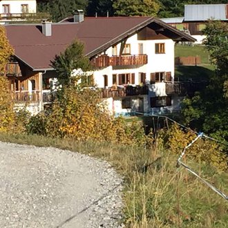 Ein idyllisches Haus inmitten von buntem Herbstlaub. Der Garten ist gut gepflegt und das Gebäude hat einen traditionellen alpinen Stil. | © Gasthof Café Alpenwald | Thorsten Alpenwald