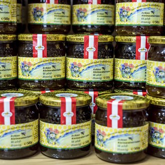 A variety of jars with jam is stacked. The jars have colorful labels with decorative designs. | © Kleinwalsertal Tourismus | Dominik Berchtold