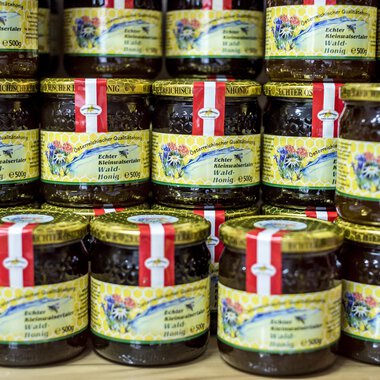 A variety of jars with jam is stacked. The jars have colorful labels with decorative designs. | © Kleinwalsertal Tourismus | Dominik Berchtold