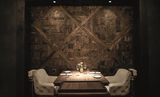 Ein elegantes Esszimmer mit einem Tisch und zwei weißen Stühlen. Die Wand im Hintergrund ist aus Holz und verleiht dem Raum eine warme Atmosphäre. | © Travel Charme Ifen Hotel