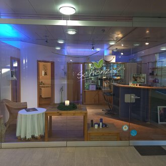 © Schönzeit | Sebastian Riezler An inviting reception area with a bright, modern design. On the table, there is a candle and there are various products on the counter. | © Schönzeit | Sebastian Riezler