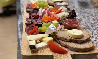 A sumptuous cheese and charcuterie board with fresh bread, grapes, bell peppers, and various dips. Ideal for a sociable snack or a party. | © Kuhstall | Uwe Nagel