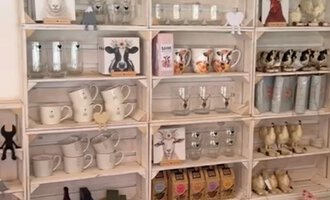 © Herzstichle | Ninja Matt Ein Holzregal voller Tassen, Kerzen und anderen dekorativen Artikeln. Im Hintergrund sind einige dekorative Berge zu sehen. | © Herzstichle | Ninja Matt