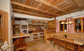 Eine gemütliche Küche mit Holzdekor und hellem Licht. Es gibt Tische, Stühle und eine Bar mit einem einladenden Ambiente. | © Michl das Steakhaus | Johannes Littich