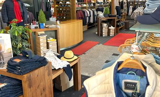 © Moosbrugger Mode e.U. Ein moderner Bekleidungsladen mit einem hellen, einladenden Ambiente. Regale voller Kleidung und Accessoires sind gut angeordnet, um den Kunden eine angenehme Einkaufserfahrung zu bieten. | © Moosbrugger Mode e.U.