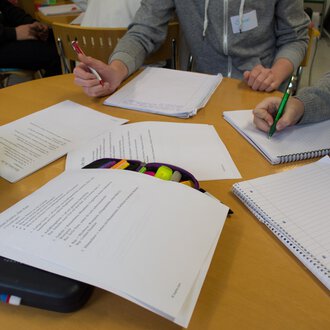 © Kleinwalsertal Tourismus A group of people is sitting at a table and working on documents. Writing, notes, and writing materials are clearly visible. | © Kleinwalsertal Tourismus