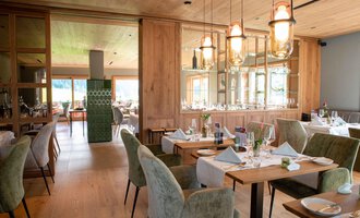 A modern restaurant with elegant wooden furnishings. The tables are lovingly set, and the lighting is warm and inviting. | © Almhof Rupp | Lukas Kind