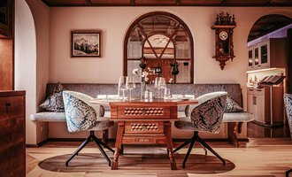 Ein gemütliches Restaurant mit einem stilvollen Tisch und elegante Stühle. Der Raum hat eine warme Atmosphäre mit Holzdetails und dekorativen Elementen.