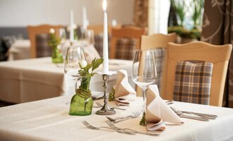 An elegantly set table with candlelight and stylish glasses. Flowers and decorative elements create an inviting atmosphere. | © Robert Haller GmbH c/o Hotel Steinbock