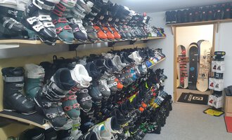 A ski rental with many ski boots on shelves. In the background, an area for snowboards can be seen. | © IFA Hotel Alpenrose