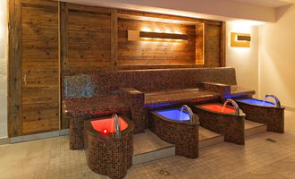 © Aparthotel Kleinwalsertal Haller GmbH & Co KG Ein eleganter Wellnessbereich mit vier Fußbädern und einer gemütlichen Sitzbank. Die sanfte Beleuchtung sorgt für eine entspannte Atmosphäre. | © Aparthotel Kleinwalsertal Haller GmbH & Co KG