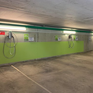 A modern underground parking garage with electric charging points. The walls are painted green and the lighting is bright. | © Naturhotel Chesa Valisa Hirschegg