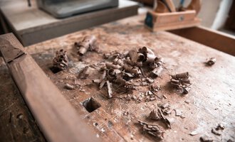 A wooden workbench with shavings and wood scraps. Tools can be seen in the background. | © Türtscher Die Schreinermanufaktur