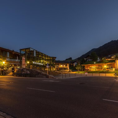 Ein malerischer Ort bei Nacht mit beleuchteten Gebäuden und sanften Hügeln im Hintergrund. Die ruhige Atmosphäre lädt zum Verweilen ein. | © Kleinwalsertal Tourismus |  Steffen Berschin