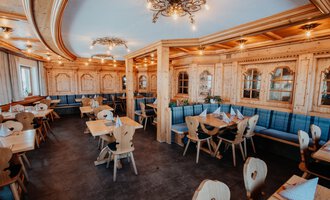 A cozy restaurant with wooden furniture and blue benches. The atmosphere is warm and inviting, ideal for social gatherings.