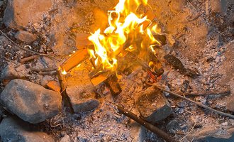 © Wildnisschule Kleinwalsertal Ein gemütliches Lagerfeuer in einem Steinkreis. Die Flammen leuchten hell und erzeugen eine warme Atmosphäre. | © Wildnisschule Kleinwalsertal
